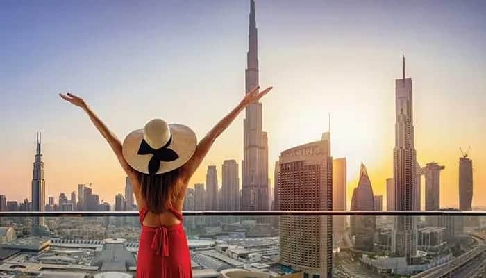Dubai skyline with woman enjoying city view at sunset.